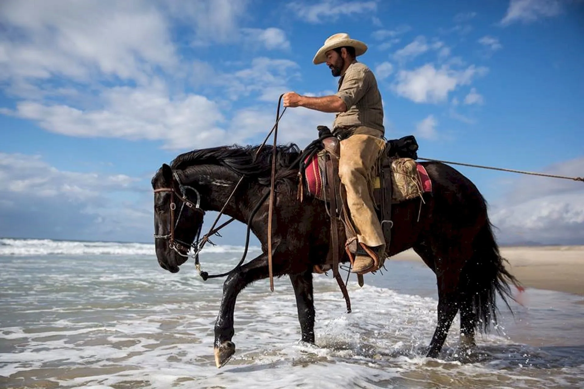 A man riding on the back of a horse in shallow water.