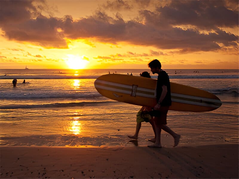 A man walking on the beach with his surfboard.