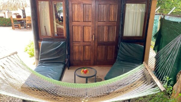 A hammock in front of two doors and a table.