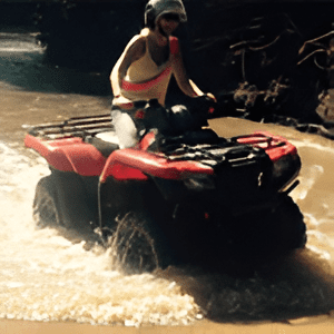 A man riding an atv through water on the beach.