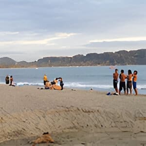 A group of people on the beach near water.