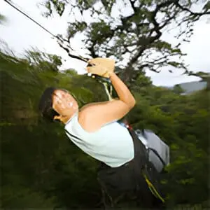 A person on a rope swing in the woods.