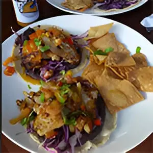 A plate of food with tortilla chips and coleslaw.